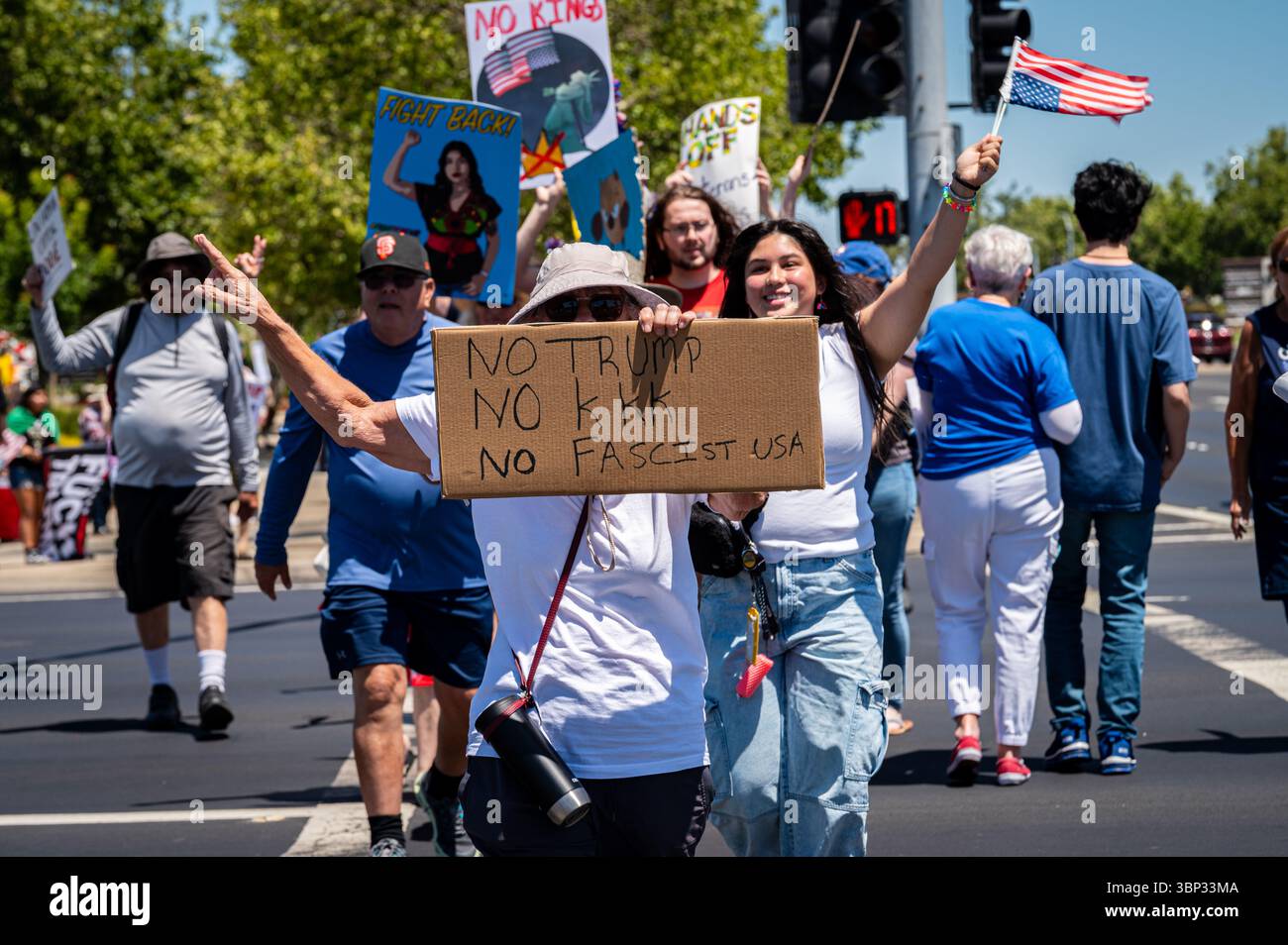 Un activiste avec un panneau sur No Trump, No KKK et No Fascist USA traverse la rue avec d'autres manifestants lors d'une manifestation du 4 juillet près de la Galleria. Banque D'Images
