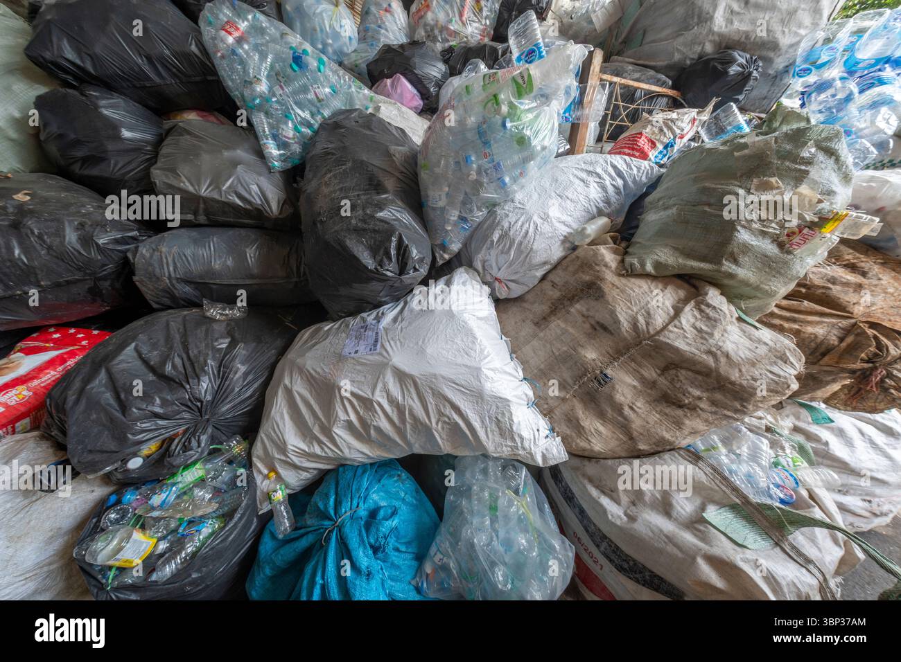Nan, Thaïlande - 8 juin 2025 - énorme pile de sacs poubelle noirs, blancs et transparents remplis de bouteilles en plastique et d'autres déchets ménagers, illustrant un pol Banque D'Images
