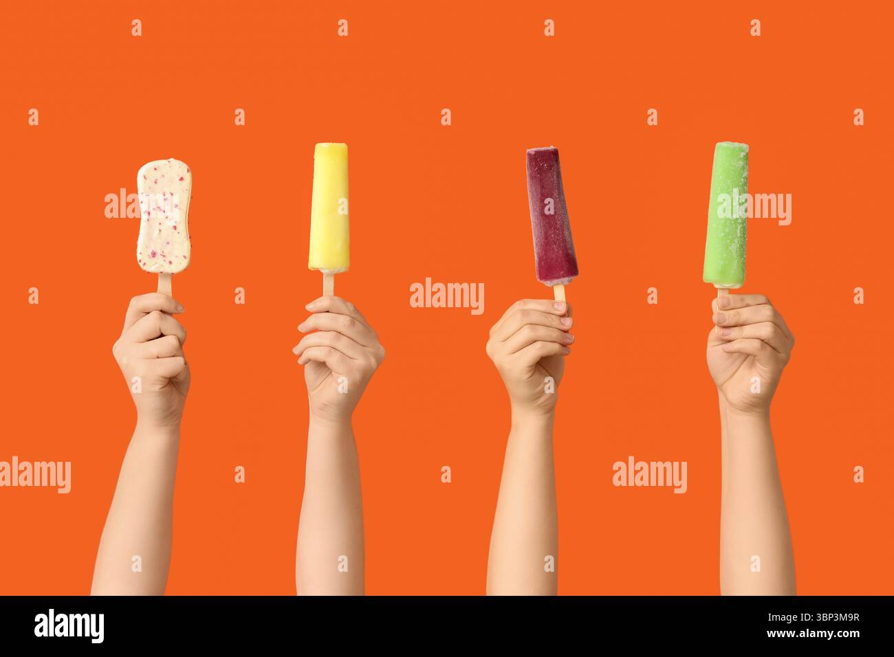 Mains féminines avec différentes glaces sucrées sur fond orange Banque D'Images