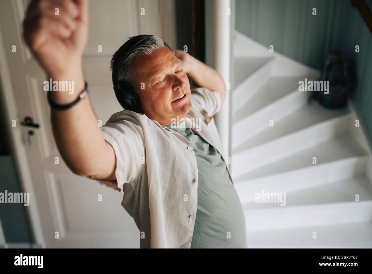 Vue en angle élevé d'un homme senior qui bouge sur la musique en portant un casque sans fil à la maison Banque D'Images