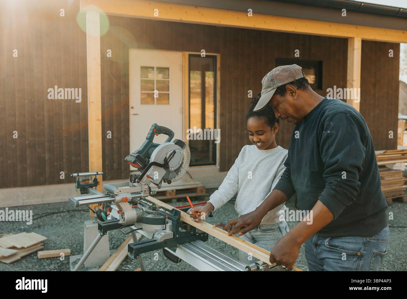 Fille souriante marquage sur planche de bois avec l'aide de grand-père pendant la rénovation de la maison Banque D'Images