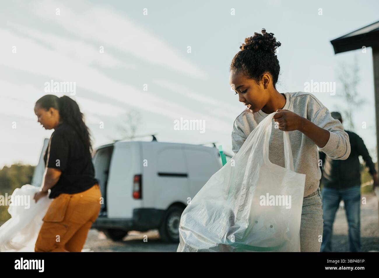 Fille ramassant les déchets de construction dans des sacs poubelles Banque D'Images