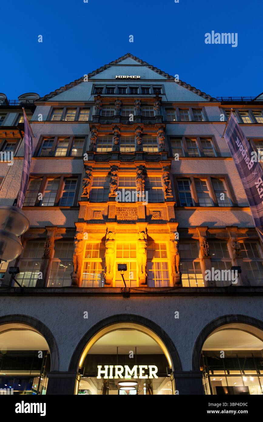 Munich, Allemagne - 3 avril 2025 : façade du magasin de vêtements Hirmer Men la nuit à Kaufingerstraße, une rue commerçante de Munich, Allemagne Banque D'Images