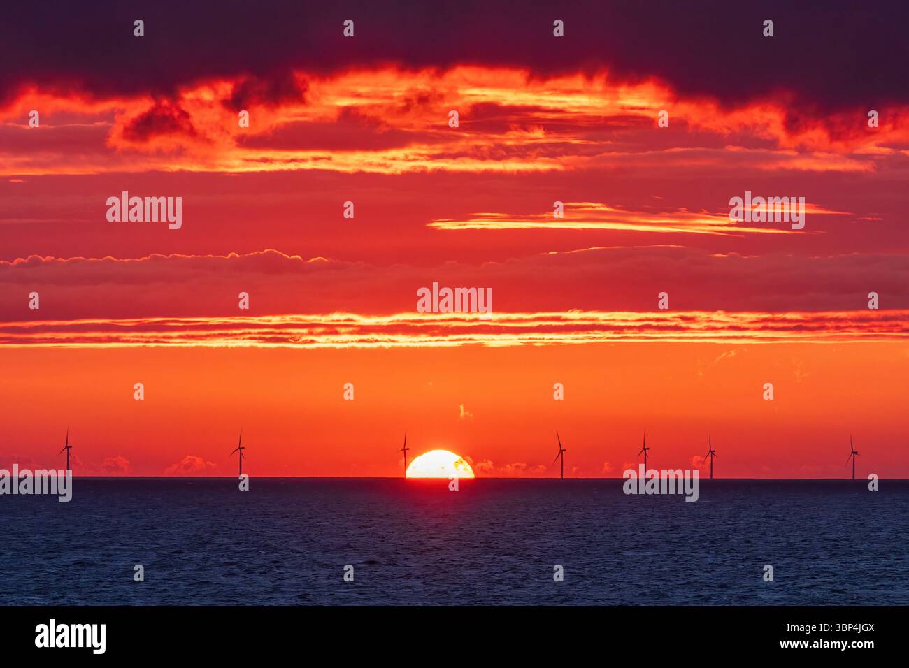 Coucher de soleil doré sur une mer norvégienne, avec des nuages spectaculaires et des reflets brillants scintillant sur la surface de l'eau calme. Une soirée paisible et atmosphérique Banque D'Images