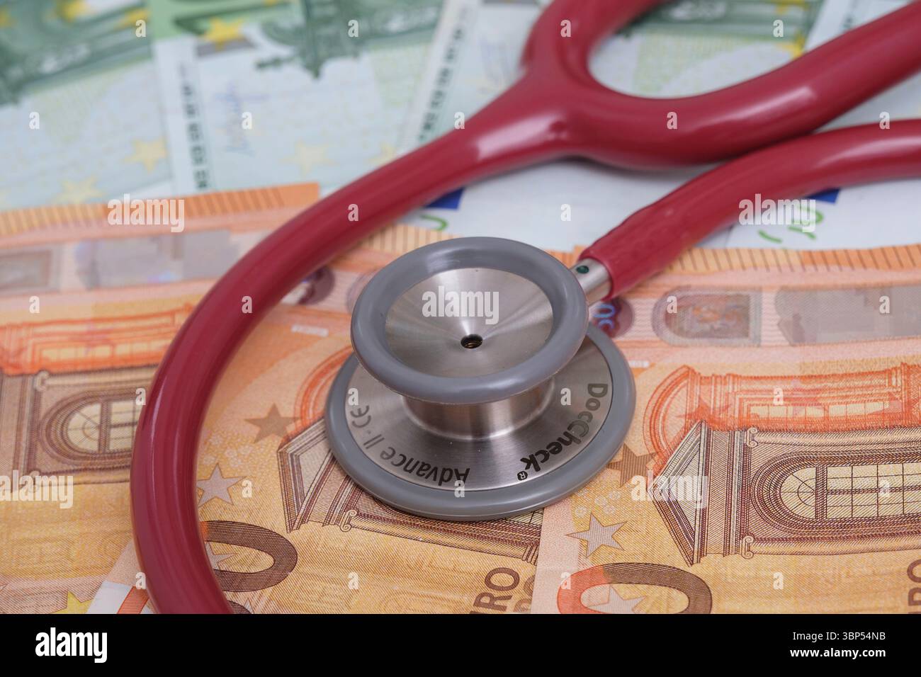 Un stéthoscope sur plusieurs billets en euros. Image symbolique de l'augmentation des coûts de santé, des dépenses médicales et des charges financières dans le système de santé. Banque D'Images