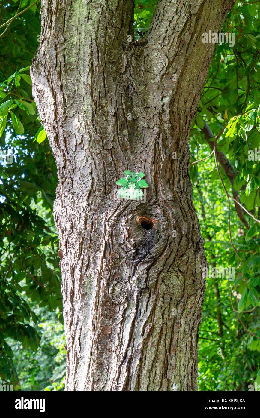 Figurine minuscule Dragon attachée à un arbre dans le cadre d'un jeu pour enfants Banque D'Images