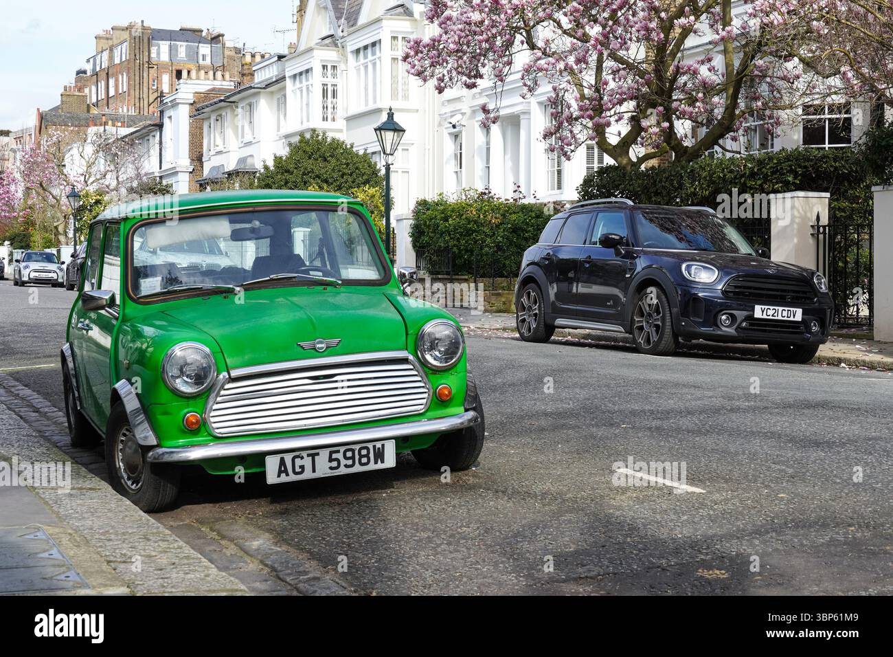 Ancienne voiture vintage Morris Mini Cooper à deux portes garée à côté de la nouvelle version moderne à quatre portes sur une rue résidentielle à Londres Angleterre Royaume-Uni Banque D'Images
