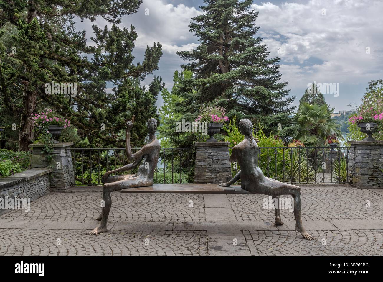 Deux personnages en bronze, connus sous le nom de « les gardiens » par Peter Lenk, sont assis sur un banc sur l'île de Mainau près de Constance, en Allemagne. Une figure pointe son doigt dans la distance, tandis que l'autre profite de la vue pittoresque sur le lac de Constance. Cette installation artistique invite les visiteurs à s’attarder et à contempler les environs Banque D'Images Deux personnages en bronze, connus sous le nom de « les gardiens » par Peter Lenk, sont assis sur un banc sur l'île de Mainau près de Constance, en Allemagne. Une figure pointe son doigt dans la distance, tandis que l'autre profite de la vue pittoresque sur le lac de Constance. Cette installation artistique invite les visiteurs à s’attarder et à contempler les environs Banque D'Images