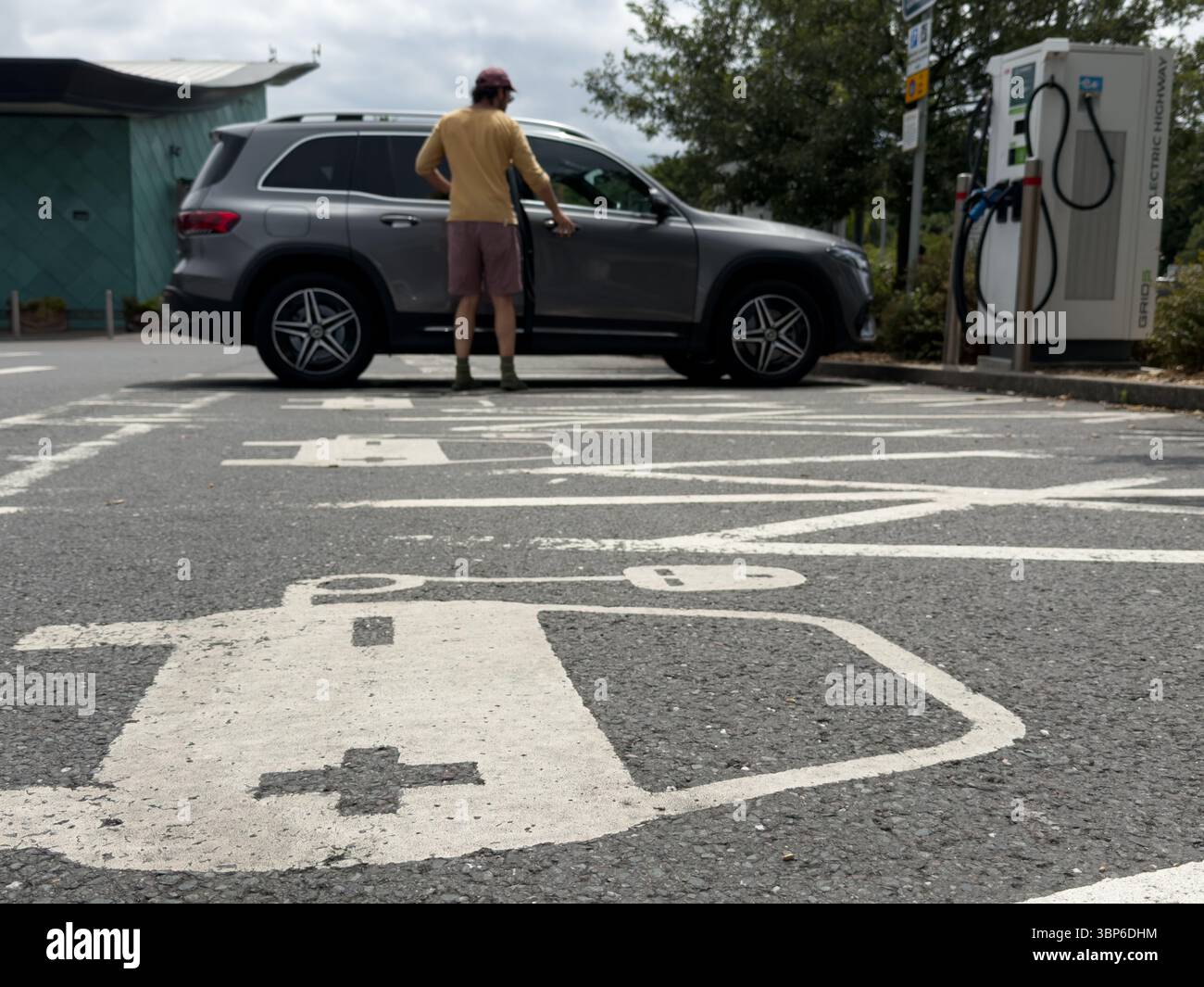 Symbole de charge de voiture électrique peint en blanc sur parking Bay alors que le conducteur se prépare à charger EV à Service Station England UK Banque D'Images