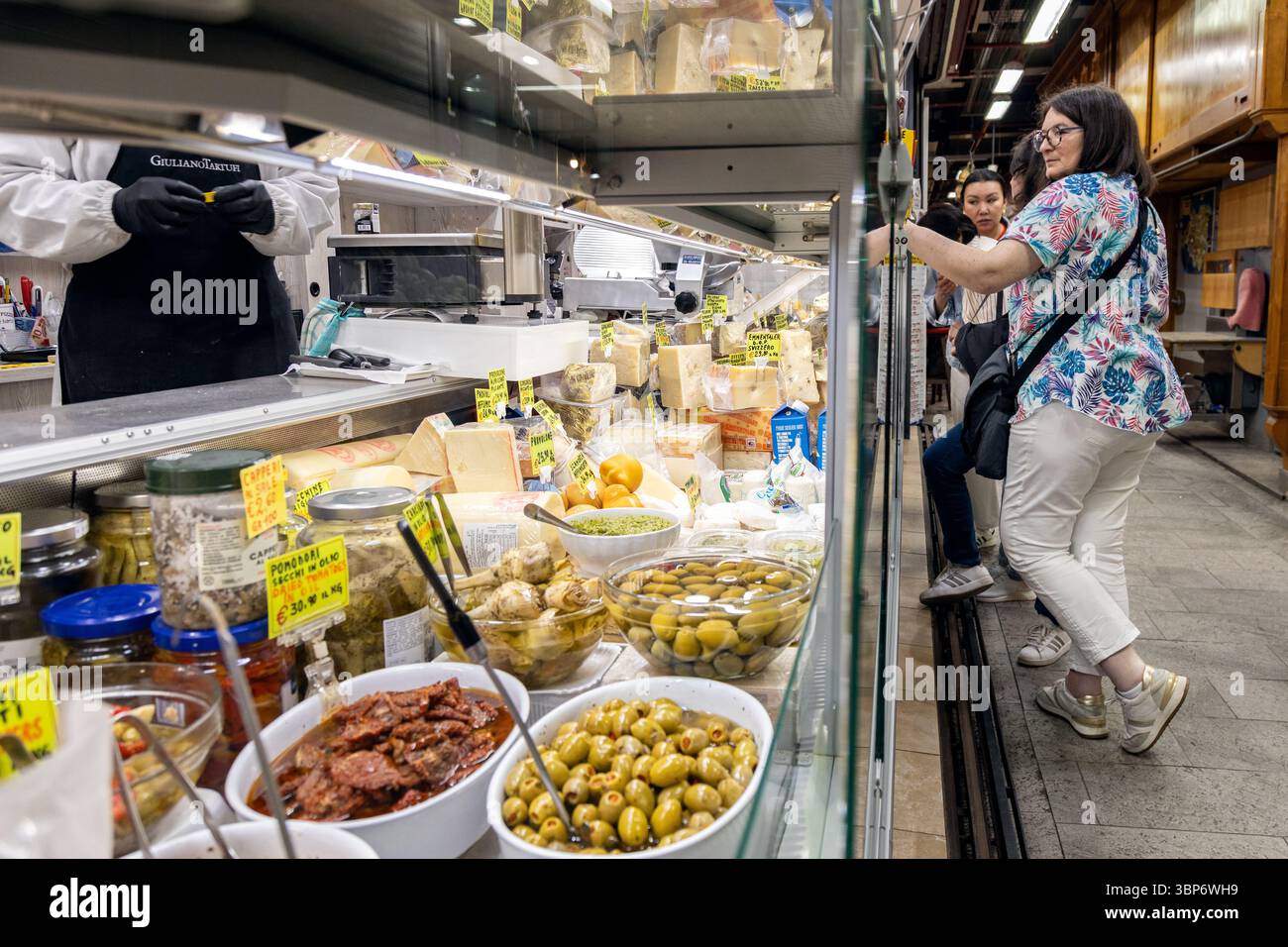 Florence, Italie - 10 mai 2025 : acheteurs à un comptoir de charcuterie avec fromages, olives et légumes conservés au Mercato centrale Banque D'Images