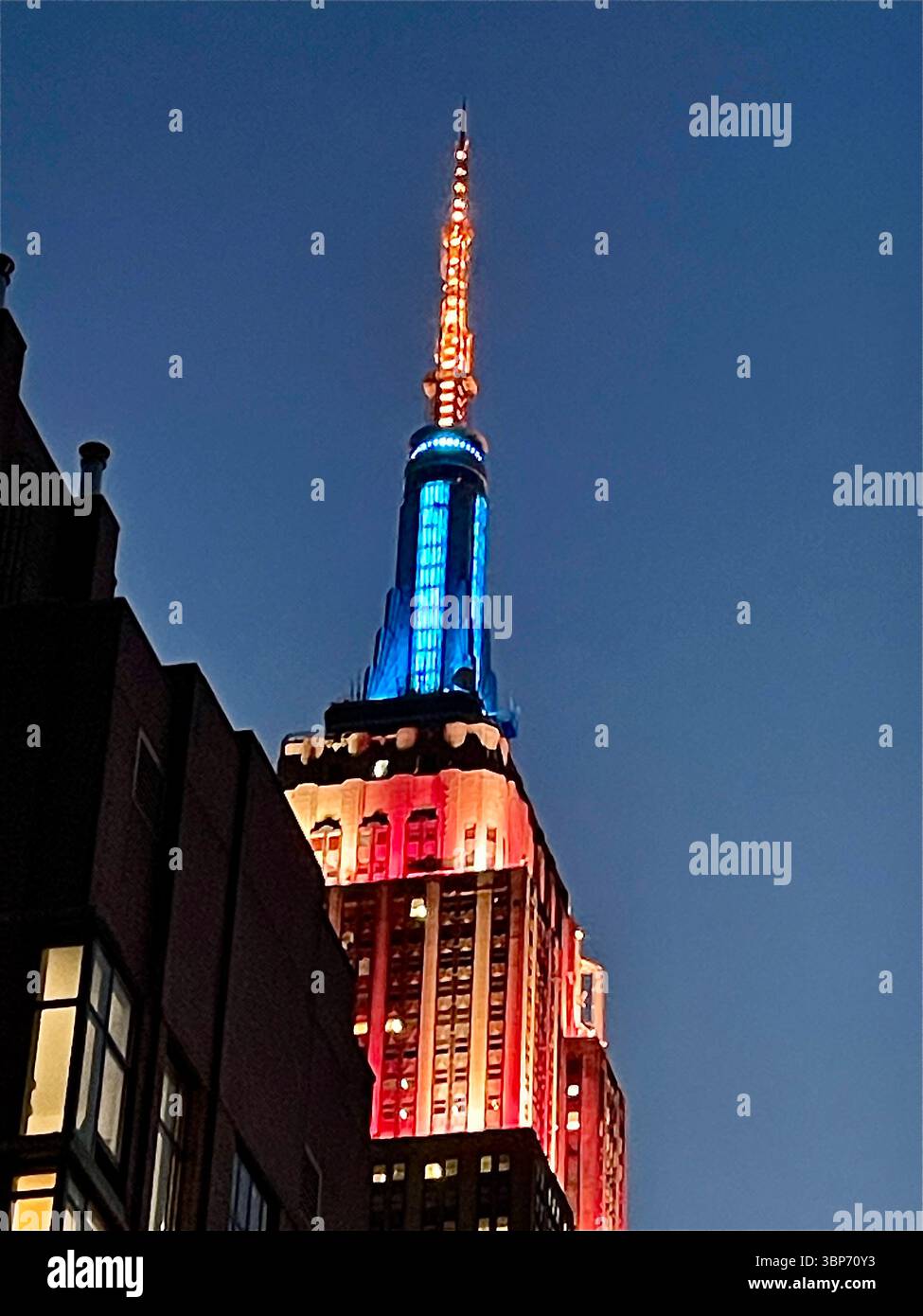 L'emblématique Empire State Building est illuminé en rouge, blanc et bleu pour célébrer le 4 juillet 2025, New York City, États-Unis - Image de stock capturée avec un smartphone