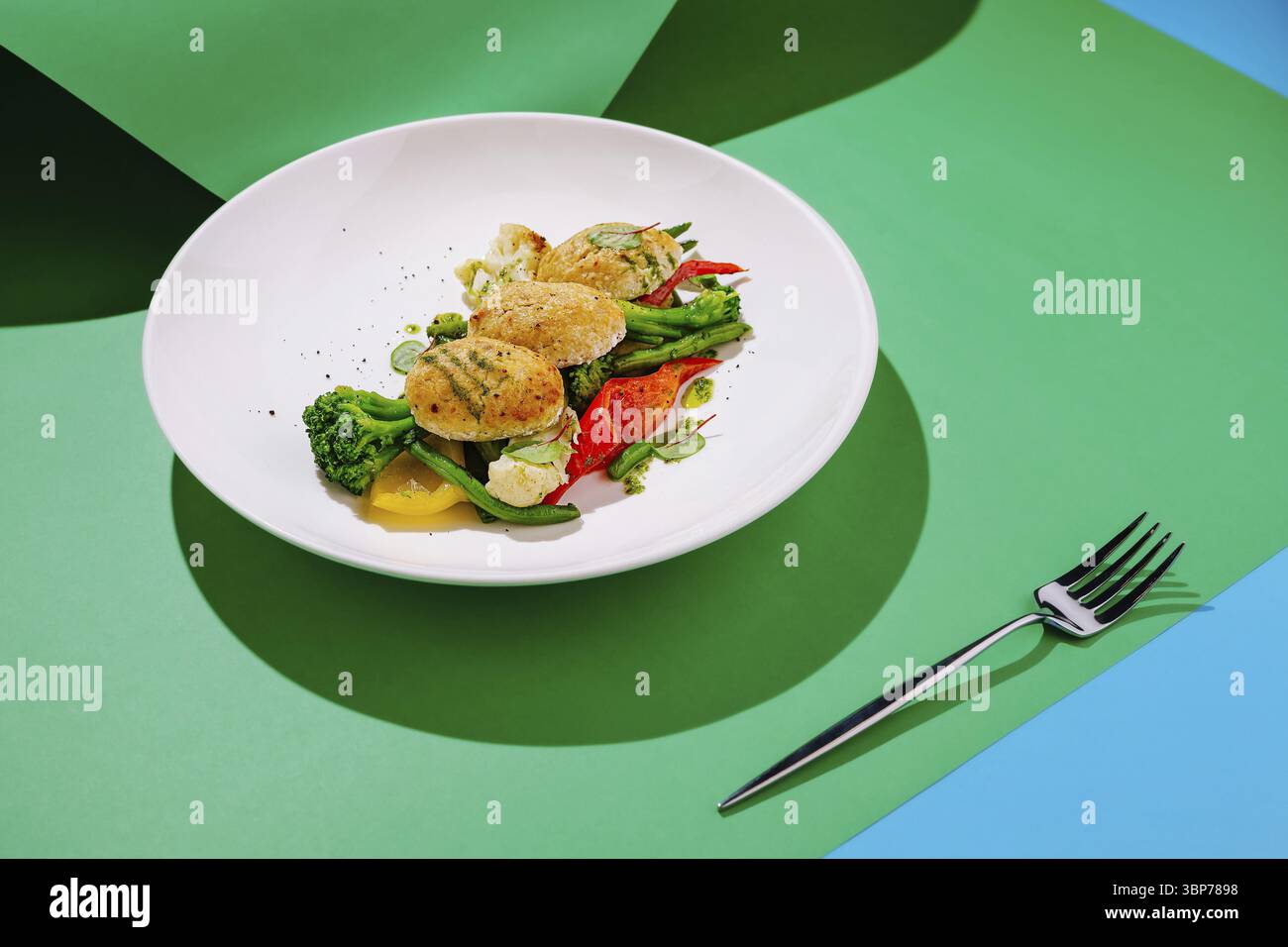 Food, Une assiette vibrante présente un plat de légumes soigneusement arrangé avec brocoli, poivrons et chou-fleur, mis en valeur par une fourchette argentée brillante, Banque D'Images