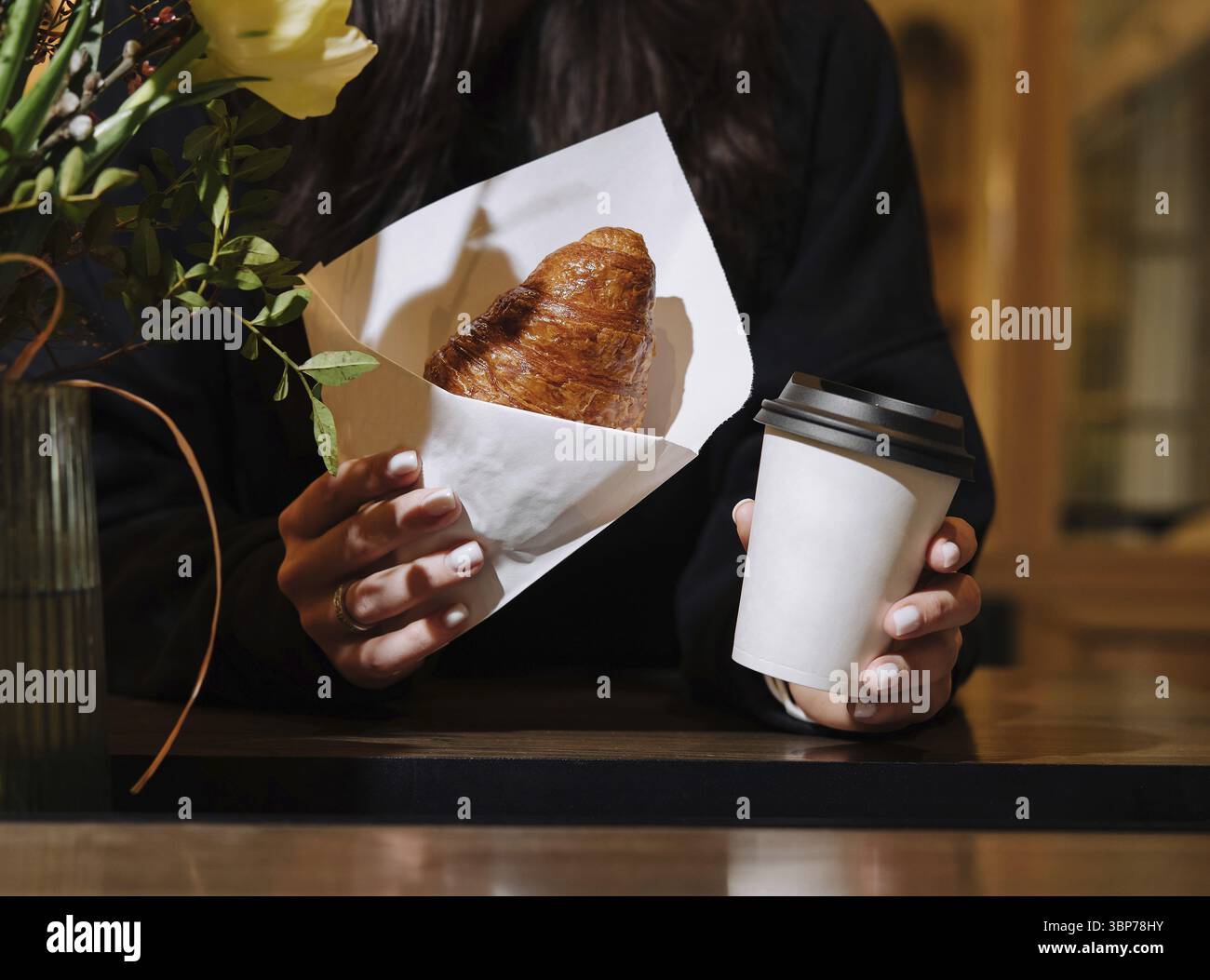 Nourriture, femme tient un croissant frais et une tasse de café à emporter Banque D'Images