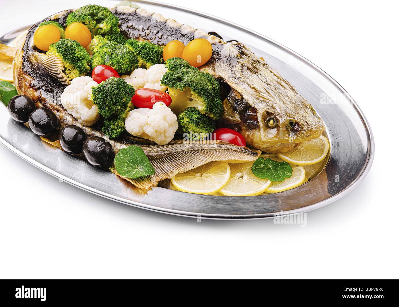 Nourriture, Un plat magnifiquement arrangé avec un poisson rôti garni d'une variété de légumes frais, y compris le brocoli, les tomates cerises et le chaume Banque D'Images