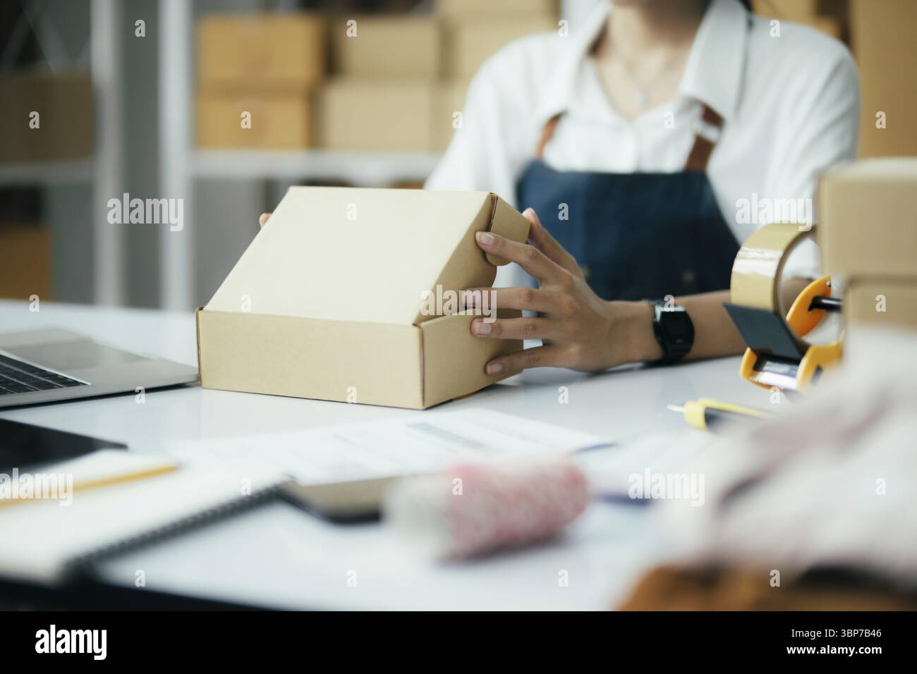 Gros plan propriétaire d'entreprise en ligne prépare le produit pour la livraison au client. Entrepreneur en ligne utilisant du ruban adhésif scotch pour sceller la boîte à colis. les petites entreprises Banque D'Images