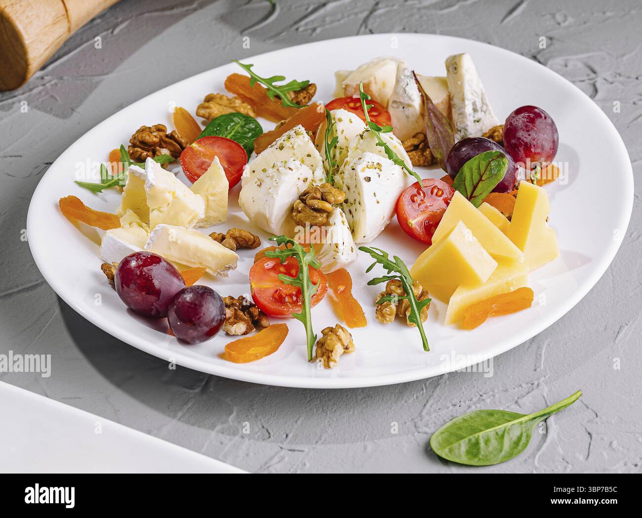 Plats, assortiment de fruits et de fromages. Gros plan d'une assiette délicieuse sur une table moderne Banque D'Images