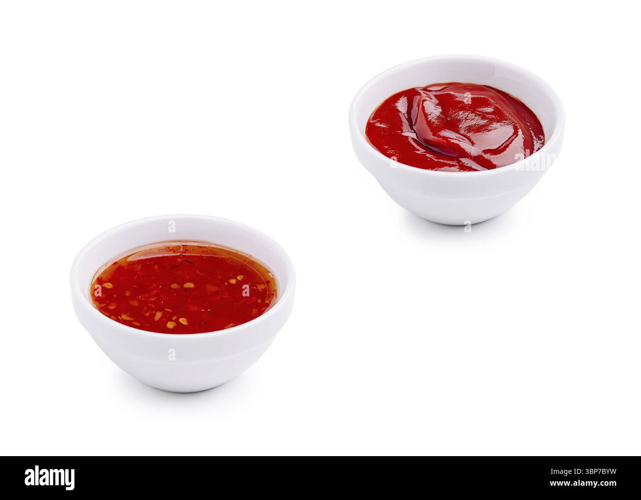 Nourriture, deux petits bols en céramique contenant des sauces rouges vives reposent sur un fond blanc. Un bol contient de la sauce Chili douce, tandis que l'autre contient des clas Banque D'Images