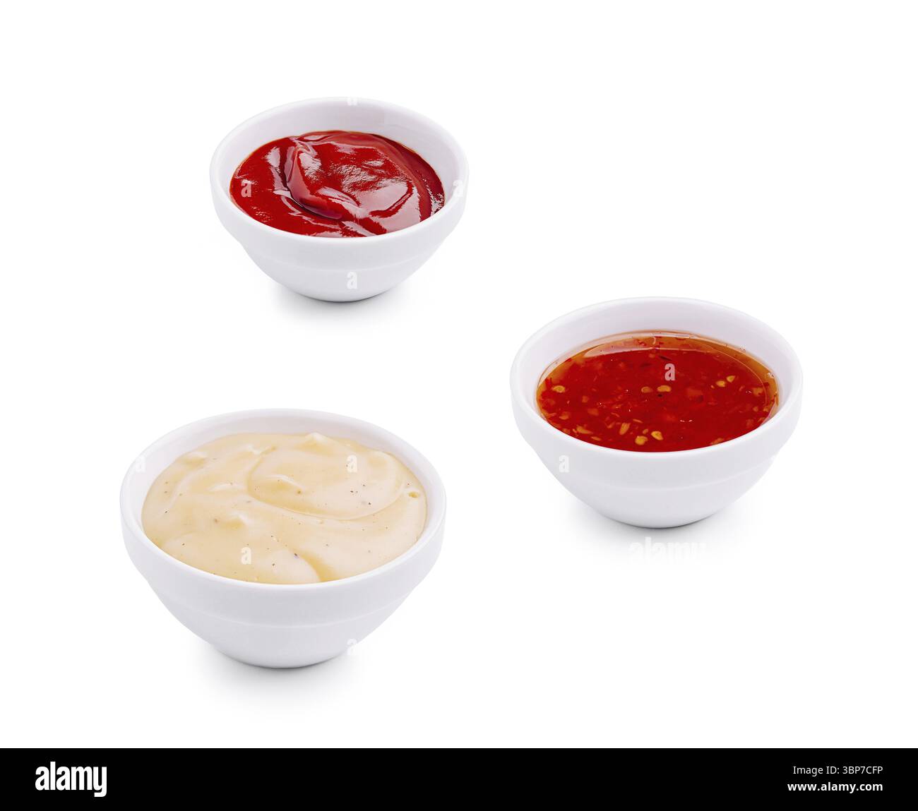 Nourriture, trois petits bols blancs contiennent différentes sauces : un riche ketchup rouge, une sauce jaune crémeuse et une sauce rouge épicée avec des flocons de piment visibles. Perfe Banque D'Images