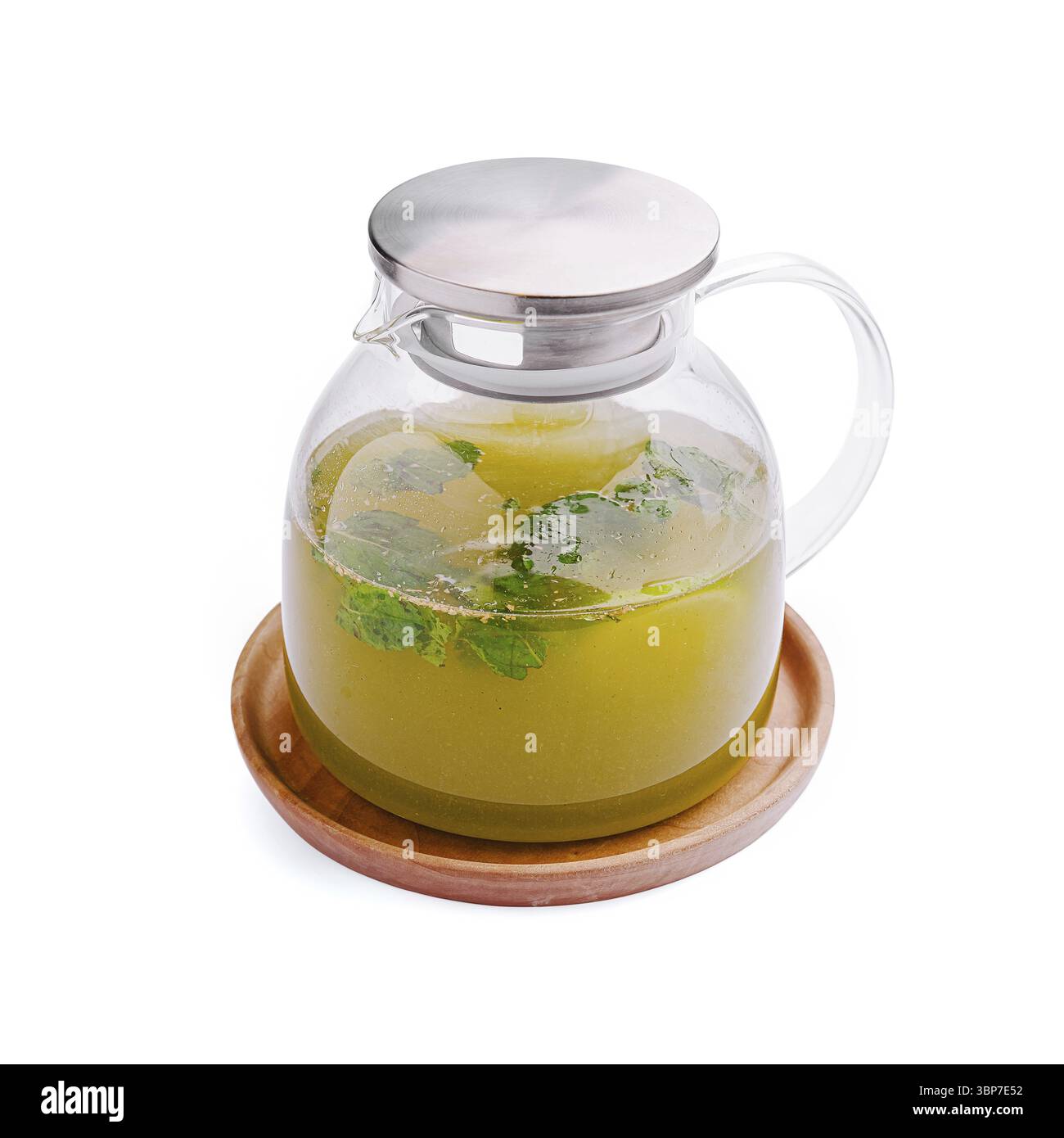 Nourriture, Un pichet en verre clair contient une tisane verte vibrante infusée de feuilles de menthe fraîche, reposant sur un plateau en bois rond. La boisson est rafraîchissante et Banque D'Images