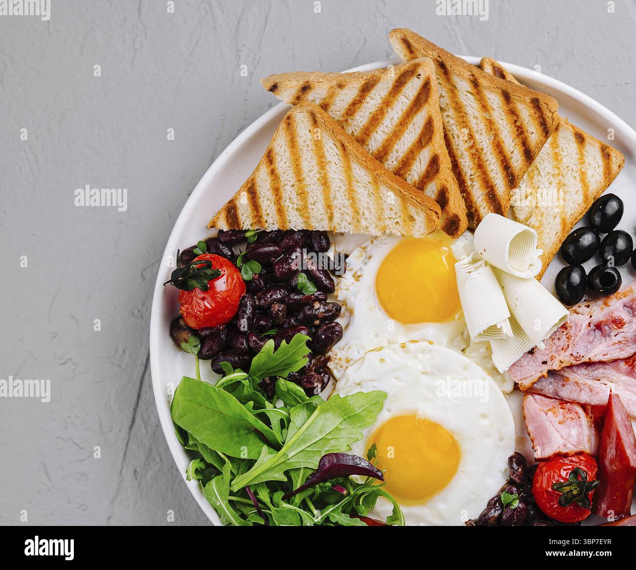 Nourriture, vue aérienne d'une assiette copieux avec œufs, bacon, pain grillé et légumes frais Banque D'Images
