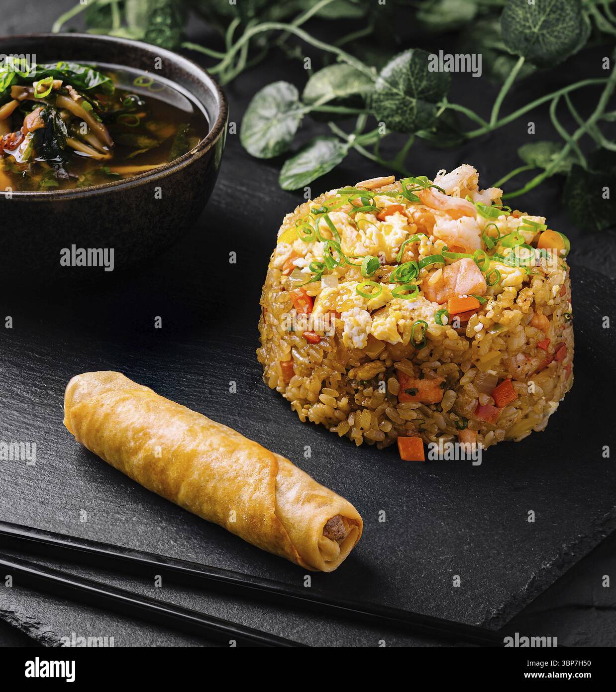 Nourriture, délicieux repas de riz frit, rouleau de printemps et soupe épicée servis sur une ardoise noire élégante Banque D'Images