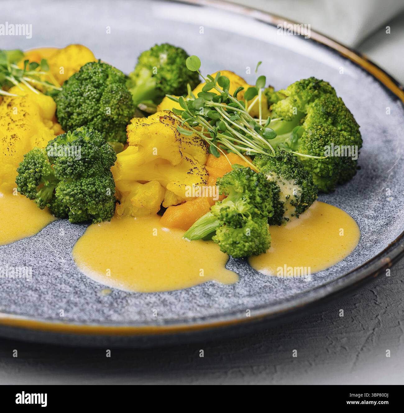 Nourriture, brocoli frais et bouquets de chou-fleur avec une vinaigrette salée sur une assiette en céramique Banque D'Images