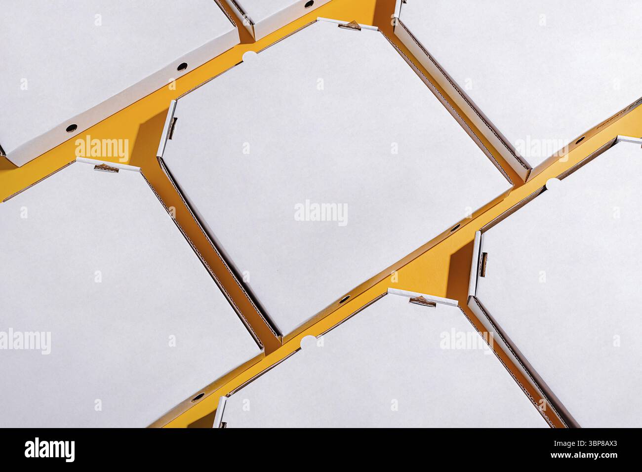 Food, Une collection de boîtes à pizza vides est soigneusement disposée sur un fond jaune vif, mettant en valeur leur design simple et propre. Les boîtes sont stacke Banque D'Images