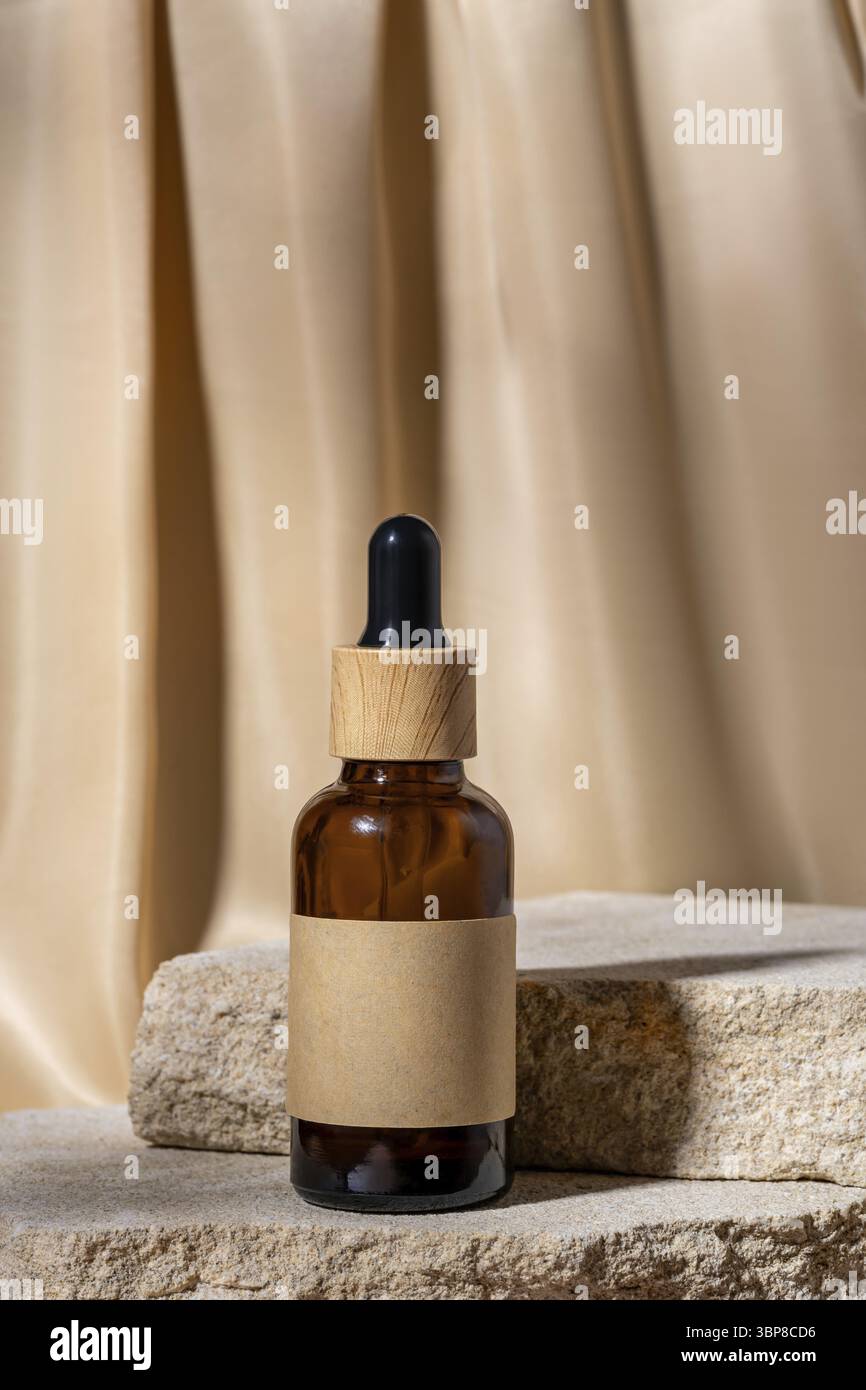 Bouteille compte-gouttes en verre avec étiquette vierge, sérum sur un support en pierre naturelle sur fond de draperie en tissu beige. Modèle de cosmétique Natural Organic Spa. minima Banque D'Images