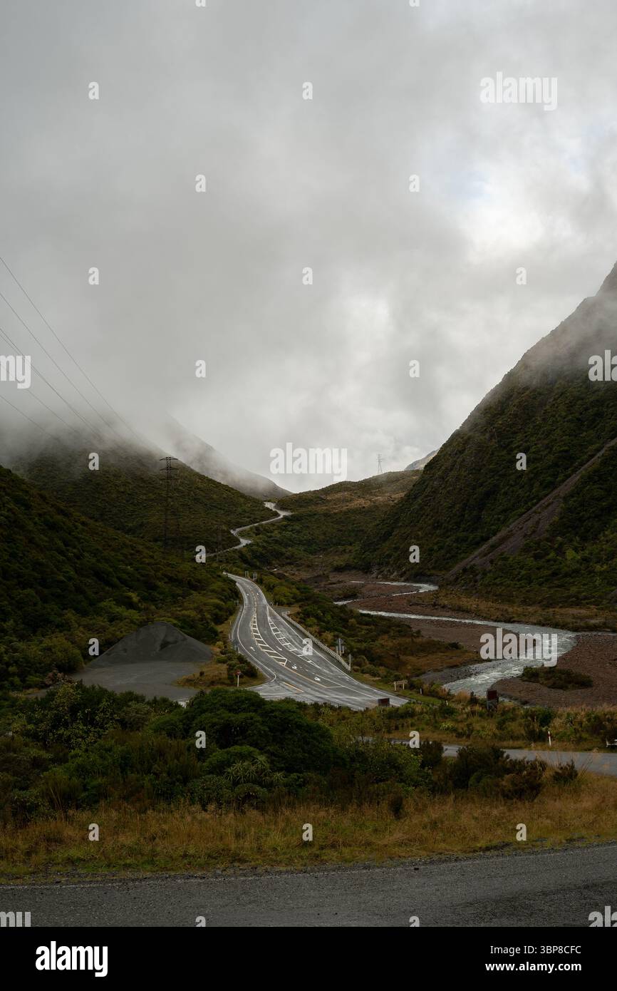 Moody, scène sereine de la vallée. Une route sinueuse serpente à travers une dense forêt émeraude entourée de brume. Un sentiment d’isolement et de beauté intemporelle, evoki Banque D'Images