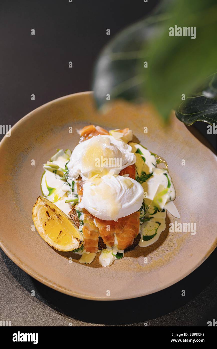 Nourriture, délicieux œufs pochés au saumon et sauce sur pain grillé sont servis dans une assiette pour un petit déjeuner sain et nutritif Banque D'Images