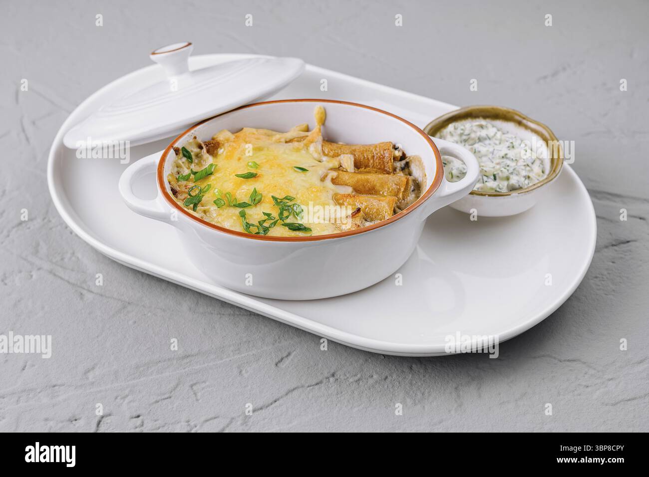Nourriture, délicieuse casserole cuite au four avec fromage fondu et herbes fraîches, servi sur une assiette blanche Banque D'Images