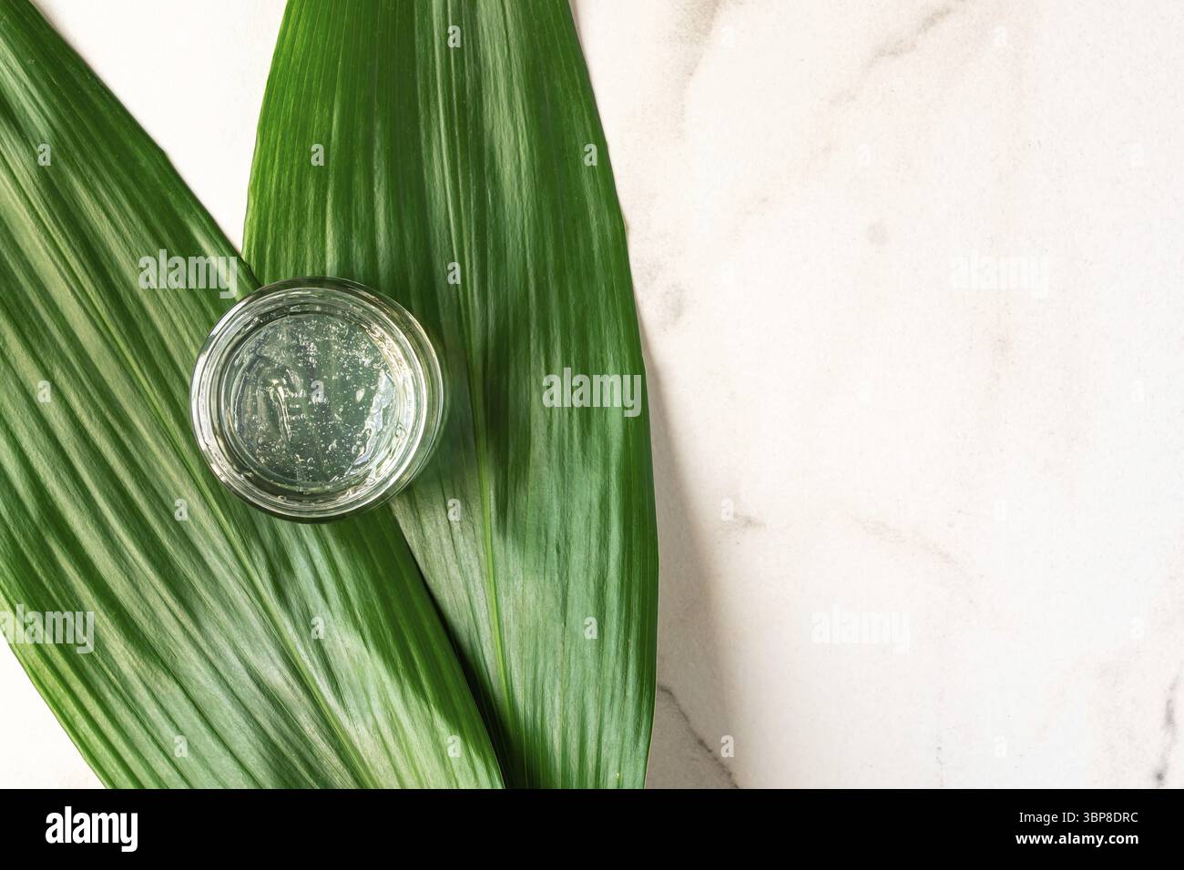 Gel transparent avec texture en bulles dans un pot transparent sur fond de marbre, vue de dessus. Cosmétiques biologiques, produit écologique pour le visage et le corps. B Banque D'Images
