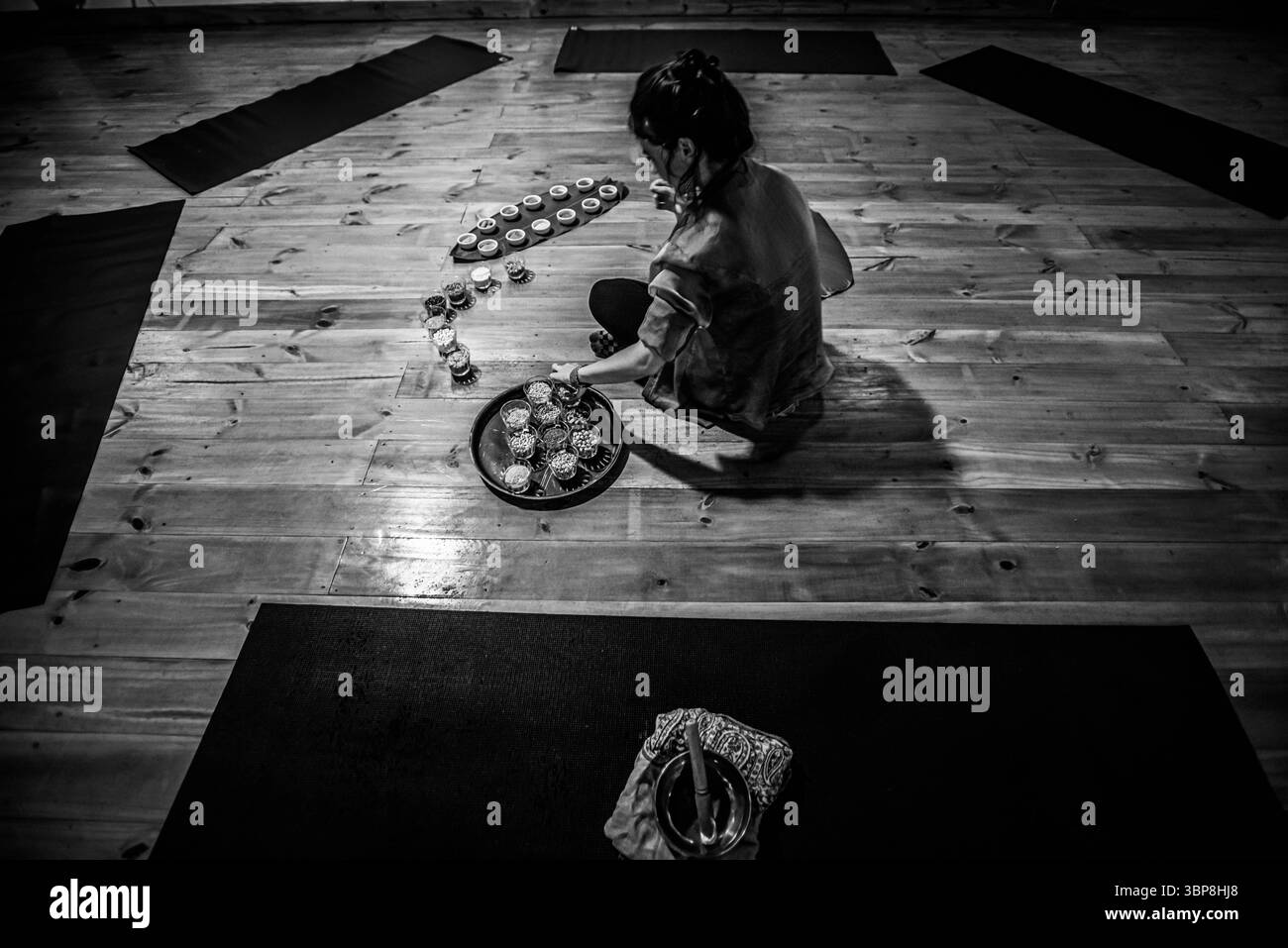 Scène monochrome de femme arrangeant des bols de grains et de poudres dans l'espace Yoga Banque D'Images