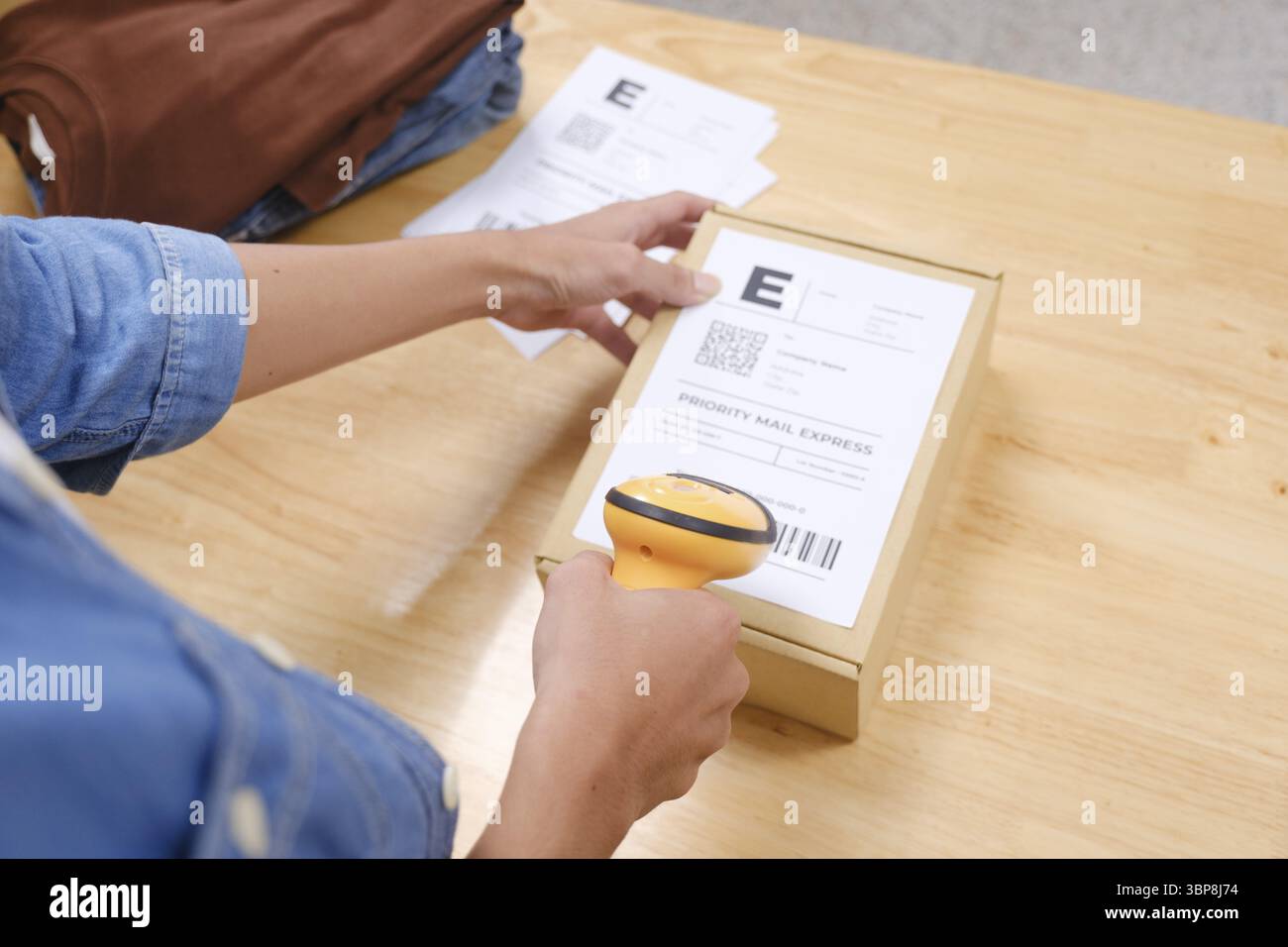 Gros plan d'une personne scannant un colis avec un scanner de code-barres, le préparant pour l'expédition dans un environnement commercial en ligne Banque D'Images