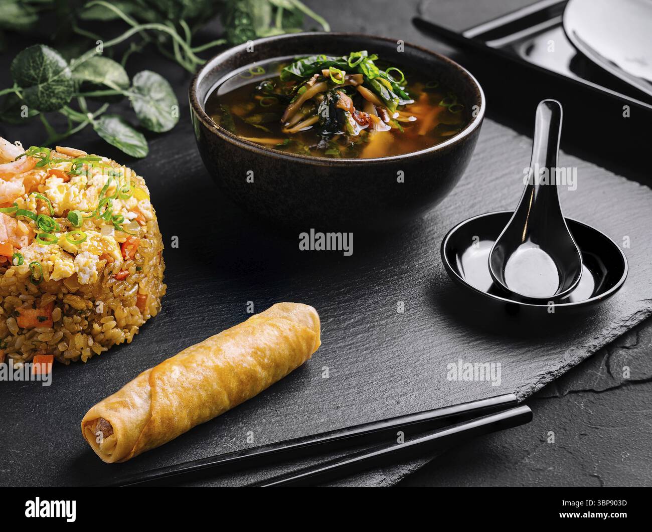 Nourriture, délicieux repas de riz frit, rouleau de printemps et soupe épicée servis sur une ardoise noire élégante Banque D'Images