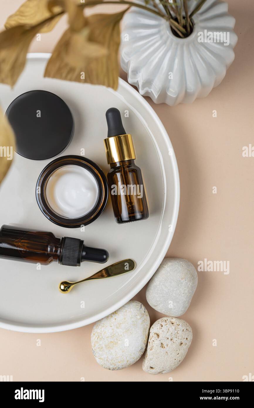 Vue de dessus des flacons de sérum sur plateau en céramique concept de vie durable, cosmétiques naturels. Présentation des produits cosmétiques sans marque. Espace de copie Banque D'Images
