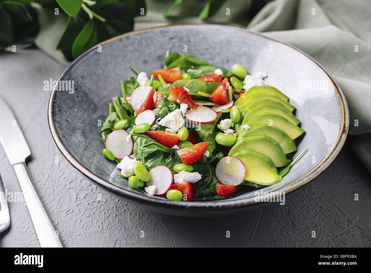 Nourriture, salade vibrante avec épinards, avocat, fraises et fromage feta servis dans une assiette moderne Banque D'Images