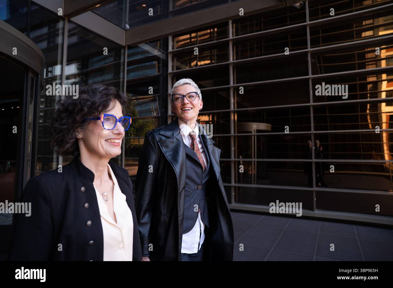 Deux femmes d'affaires souriantes et marchant à l'extérieur de l'immeuble de bureaux Banque D'Images