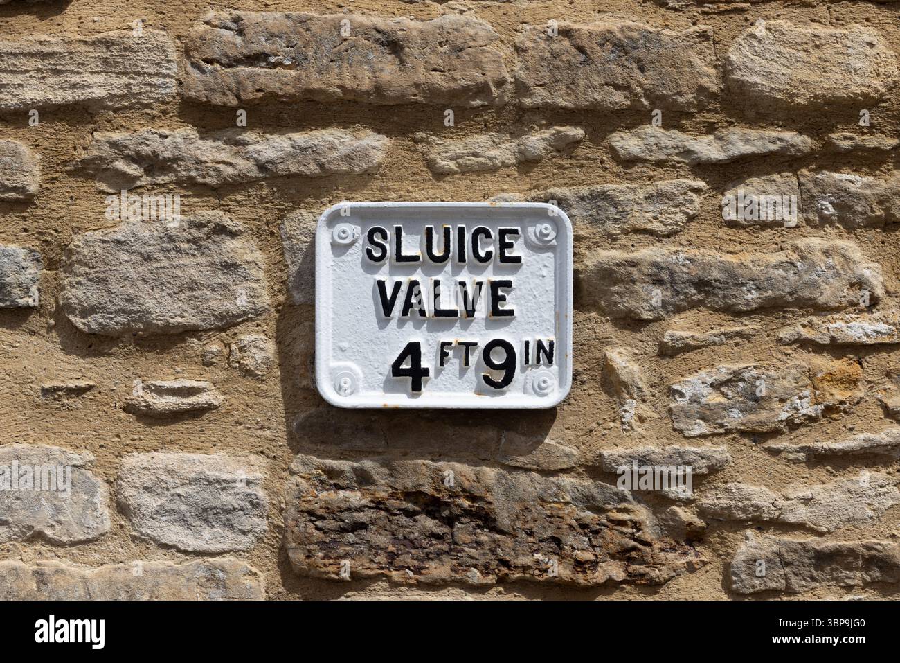 Vieux signe de vanne d'écluse en métal sur le mur de pierre Banque D'Images