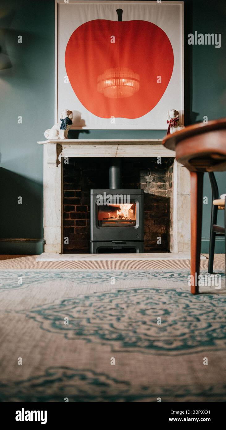 Une cheminée avec une peinture de pomme rouge sur le mur. La cheminée est allumée et la peinture à la pomme est un point focal de la pièce Banque D'Images