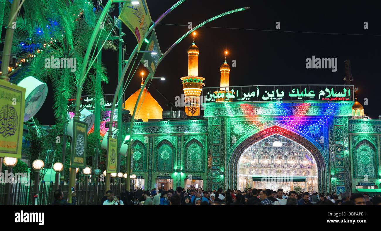 Des milliers de pèlerins et de visiteurs marchent vers le sanctuaire de l'Imam Hussein à Karbala, reflétant l'atmosphère vibrante de la nuit. Banque D'Images