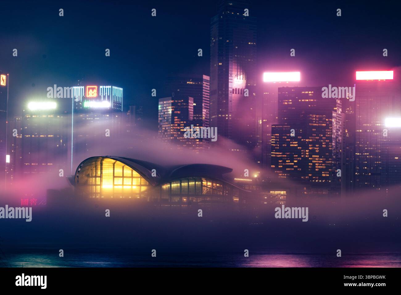 Le brouillard enveloppe Victoria Harbour, Hong Kong, créant une atmosphère cyberpunk avec des néons illuminant la ligne d'horizon, mêlant modernité et mystère. Banque D'Images