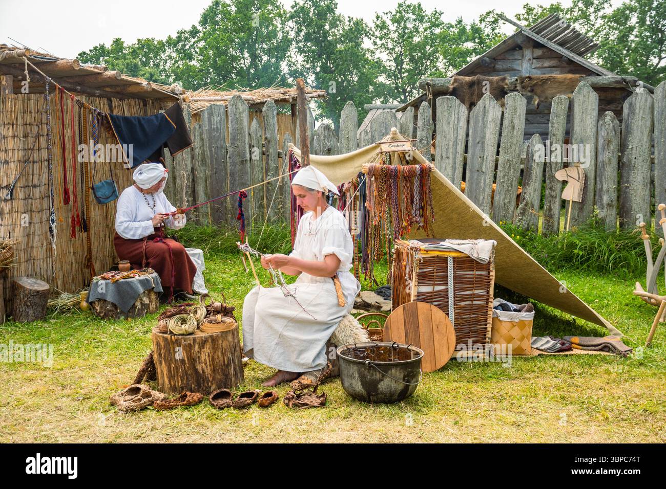 Une femme en vêtements médiévaux lors d'une fête médiévale fabriquant des chaussures avec le cuir en utilisant une vieille technique utilisée au moyen âge Banque D'Images