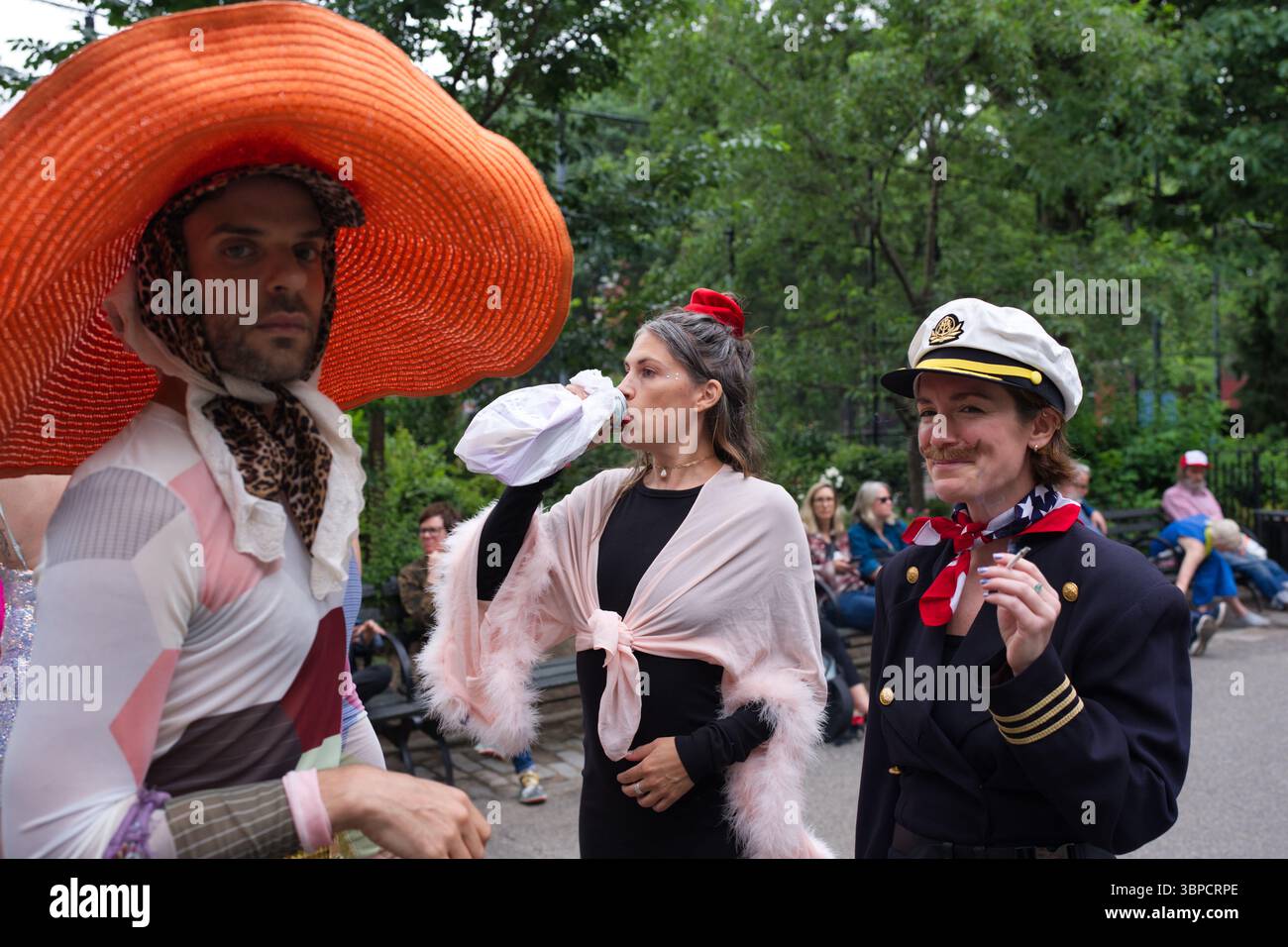 Trois individus en tenue vibrante sont capturés à l'extérieur. L'un porte un grand chapeau orange et des vêtements à motifs ; l'autre, un châle rose et un vêtement foncé Banque D'Images