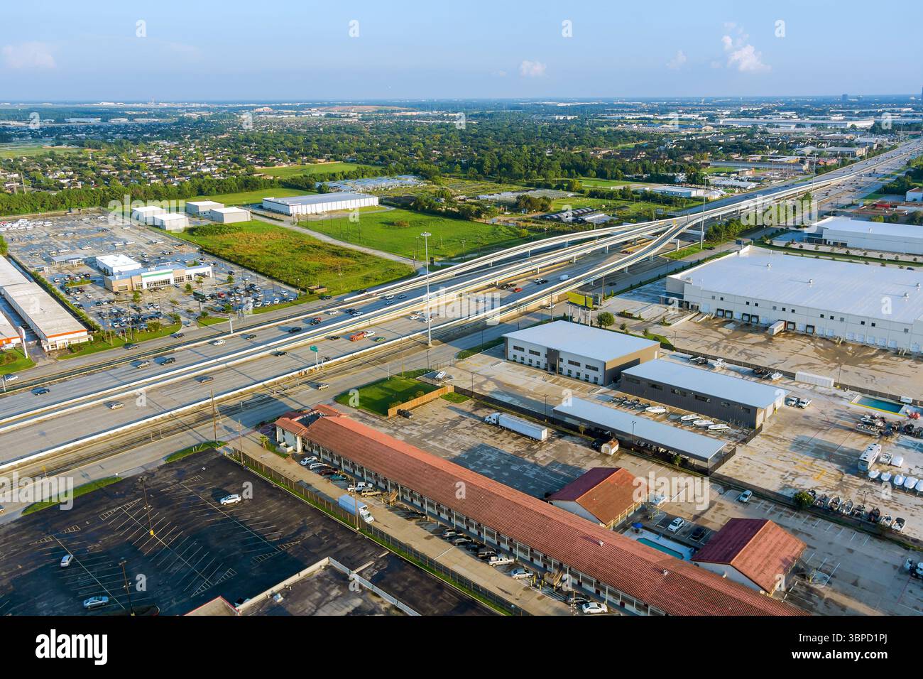 Intersection complexe d'autoroutes à plusieurs niveaux avec entrepôts industriels, parkings, paysage de banlieue environnant à Houston, comté de Harris, Texas. Banque D'Images