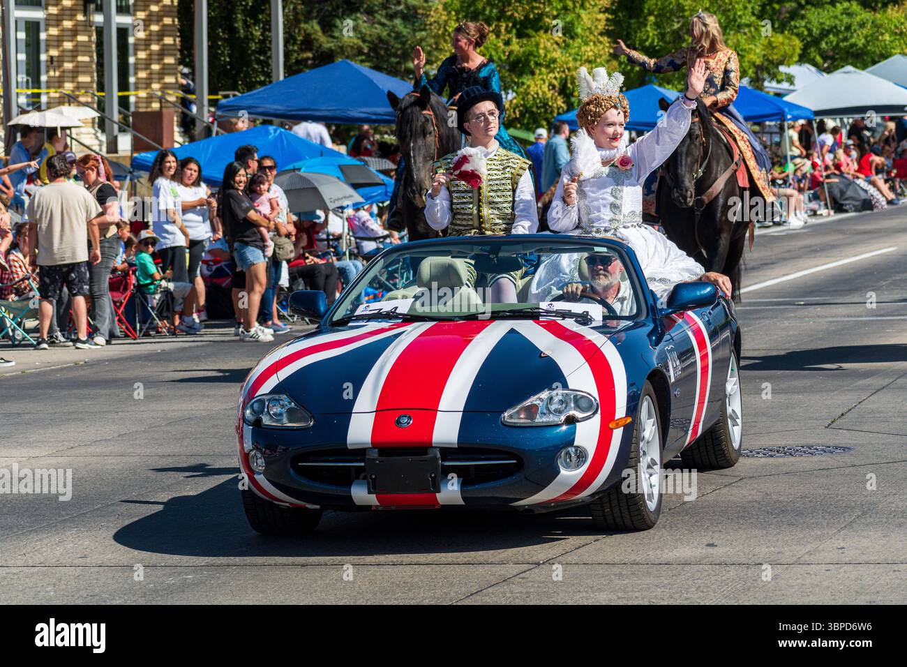 Provo, UT – 4 juillet 2025 : des gens en costumes de style européen montent dans une Austin Healey classique avec un drapeau britannique pendant le Freedom Festival. Banque D'Images