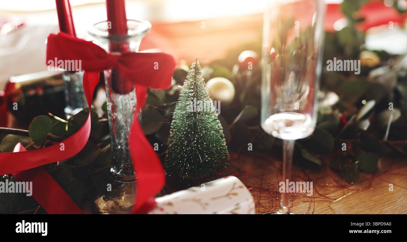 Noël, décorations et coupe de champagne sur table dans la salle à manger pour une fête, un événement ou un déjeuner festif. Vacances, lieu de mise en place et arbre pour Noël Banque D'Images