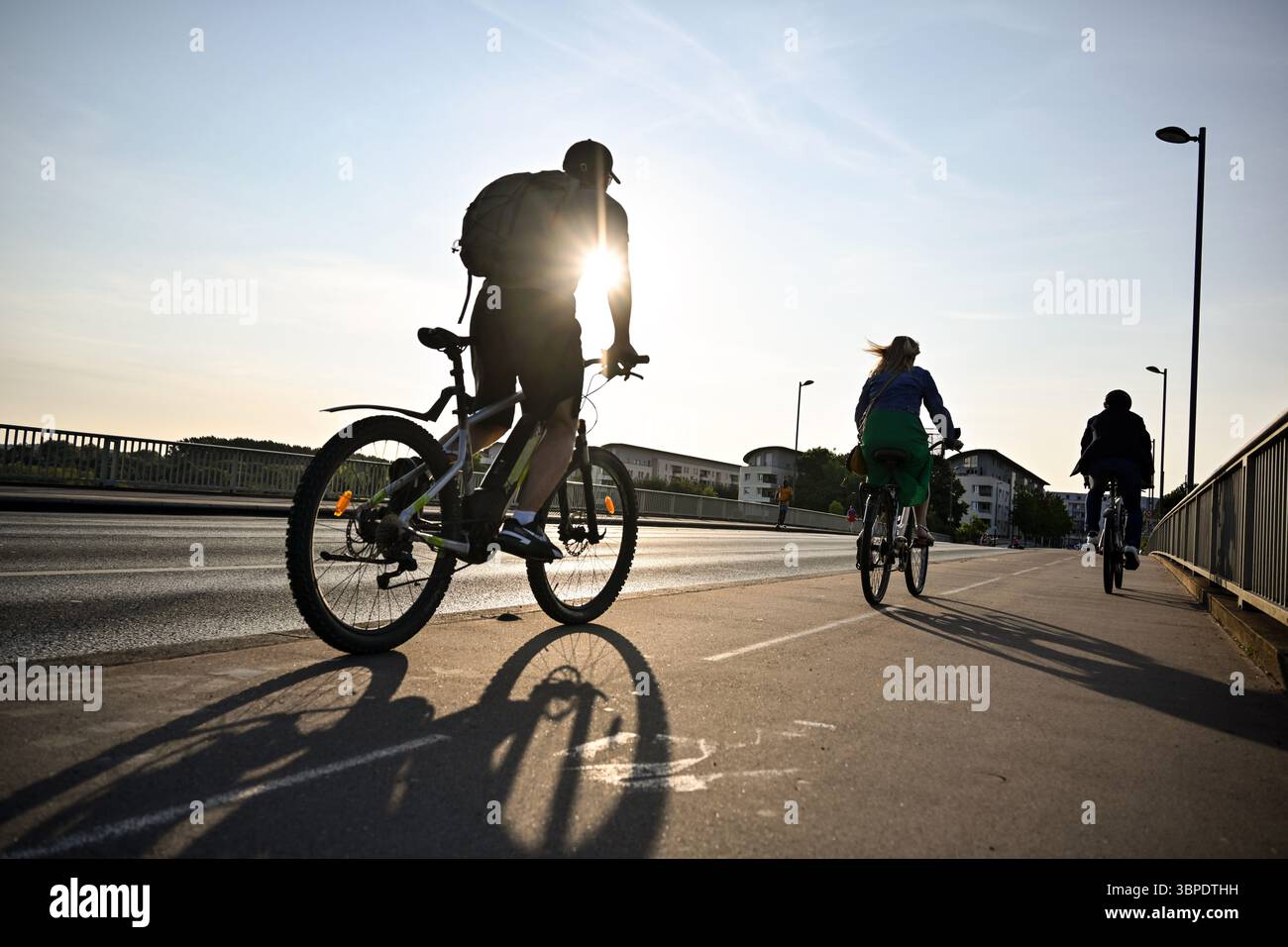 Angers (nord-ouest de la France) : cyclistes au coucher du soleil, sur une piste cyclable de pont. Vélos de ville et VTT Banque D'Images