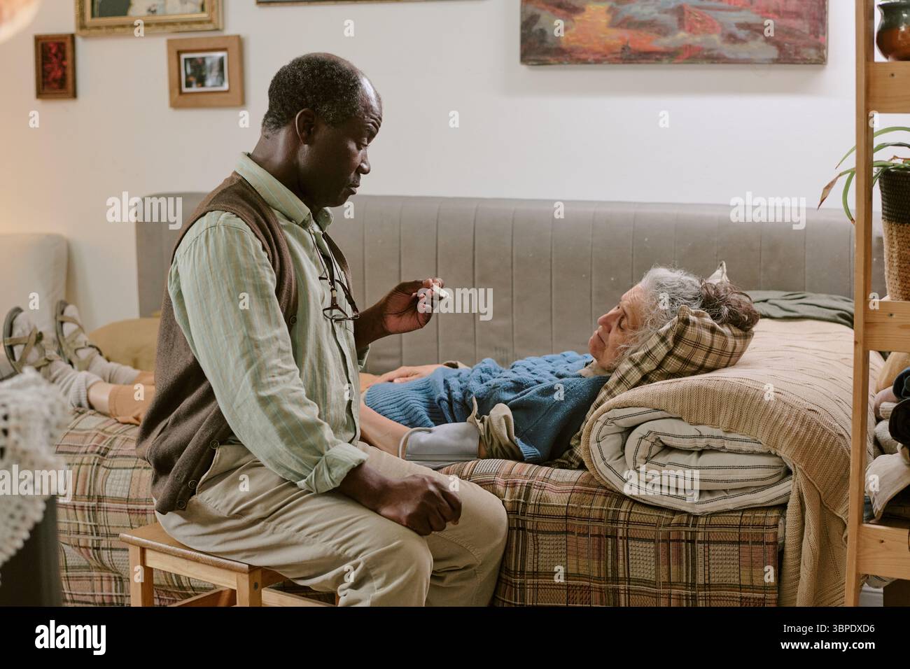 Homme noir senior réconfortant femme caucasienne senior reposant sur le lit à l'intérieur Banque D'Images