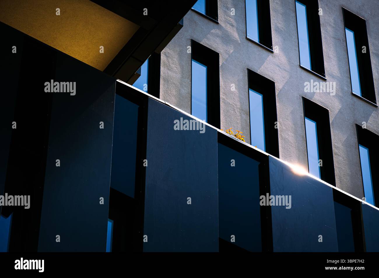 Façade de bâtiment minimaliste avec un fort jeu de lumière et d'ombre sur les surfaces bleu foncé et gris Banque D'Images